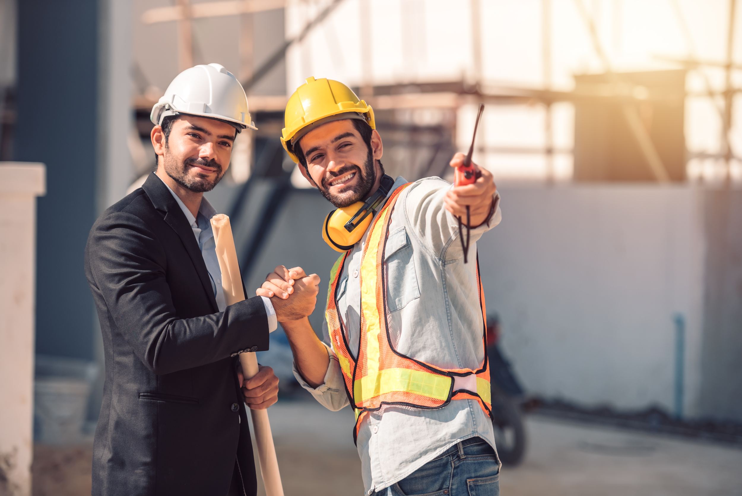 Happy workers at construction site, young civil engineer manager and architects handshaking at construction site and looking to next construction phase , cooperation teamwork concept.